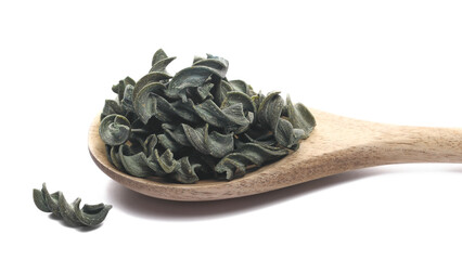 Uncooked fusilli spirulina in wooden spoon, organic dry pasta isolated on white, side view