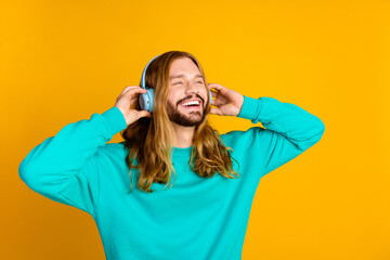 Photo of positive person toothy smile hands touch headphones listen new single isolated on yellow color background