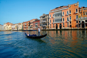 A man driving a gondola through the canals of Venice, Italy. Tourism in the city of Venice. Unesco World Heritage. Transport on the waterways of Venice. © stu.dio