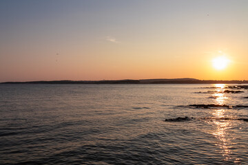 Beautiful sunset at rocky beach in coastal town Medulin, Istria peninsula, Croatia, Europe. Romantic view of rugged coastline Kvarner Gulf in Adriatic Mediterranean Sea in tranquil summer. Tranquility