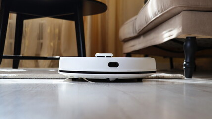 Robotic vacuum cleaner on laminate wood floor and the carpet in living room