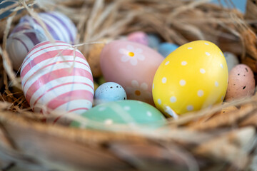 Colourful easter eggs in a basket. Stripey and dotted design with yellow, pink, green and blue colors. Straw basket.