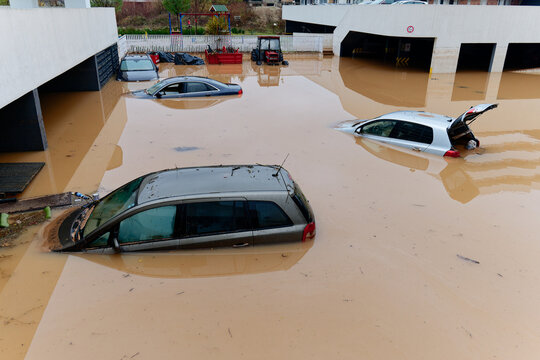 Torrential rain causes flash floods in the city area. Cars under water in the condominium parking lot. Damaged cars caused by heavy rainfall. Buildings surrounded by water.