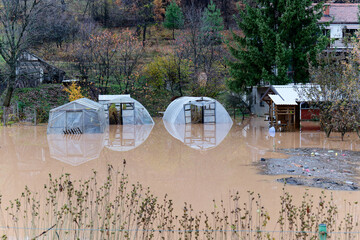 Torrential rain causes flash floods in residential areas. House surrounded by water. Plantation and...