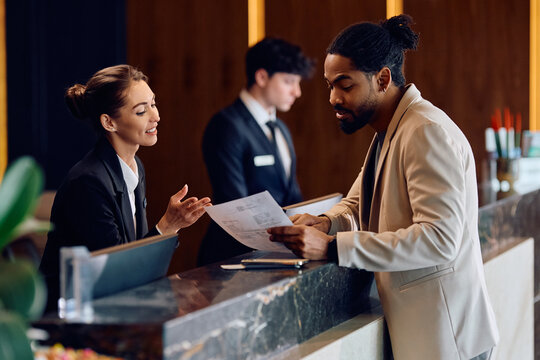 African American man checking in at reception desk in hotel.