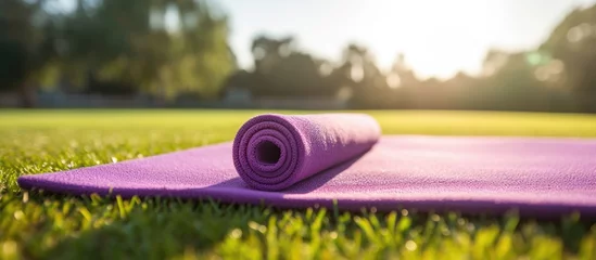 Gordijnen Purple yoga mat on grass under sunlight © Ilgun