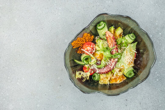 octopus salad, seafood and vegetables on a light background, top view. copy space
