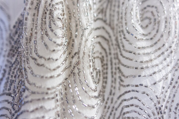 Closeup texture of beading pattern detail on white wedding gown