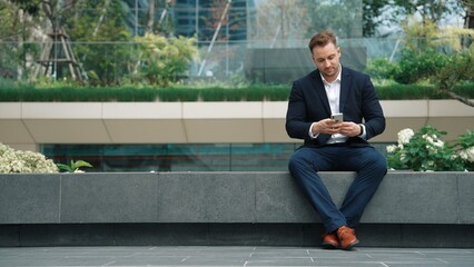 Caucasian businessman sitting at park while talking to investors about marketing strategy. Happy...