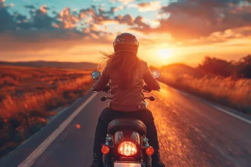 Fototapeten Scenic view of a person on motorcycle driving towards the sunset on a countryside road, warm tones and clear sky © svastix