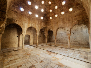 Interior view of the Arabic Baths El Banuelo, in Granada Spain. Sunlight entering the ceiling. Old and historic interior of Arab baths. Moorish architecture. - obrazy, fototapety, plakaty