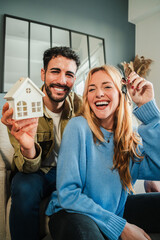 Vertical. couple celebrating a beginning at their new home holding the key of the house. Real...