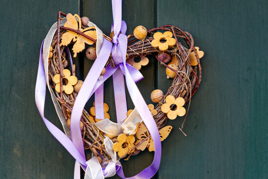 Close-up of wooden green door with heart flower decoration on a sunny spring day. Photo taken March 20th, 2024, Zurich, Switzerland.