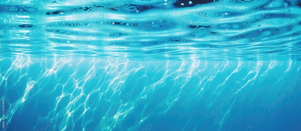 Poster a detailed view of a surface of blue water showing gentle ripples and tiny bubbles floating on the t