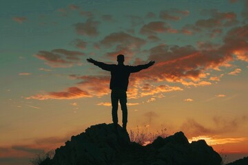 A man's silhouette stands triumphantly on a rocky outcrop, with a dramatic orange sky as the backdrop, evoking a sense of achievement and solitude.