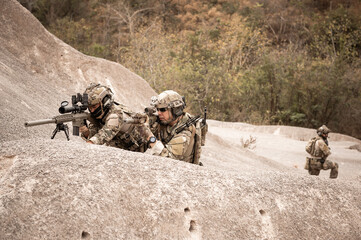 Fototapeta premium Soldiers in camouflage uniforms aiming with their rifles.ready to fire during military operation in the desert , soldiers training in a military operation