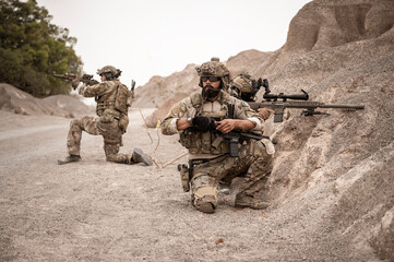 Soldiers in camouflage uniforms aiming with their rifles.ready to fire during military operation in...
