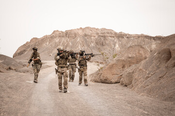 Soldiers in camouflage uniforms aiming with their rifles.ready to fire during military operation in...