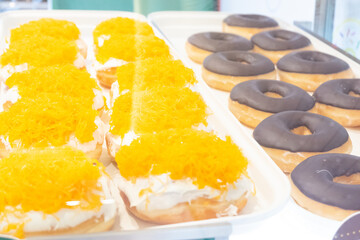 Display of delicious pastries in a bakery with assorted glazed donuts,Various donuts on shelf in Bakery, donuts in showcase of typical pastry shop in the street.