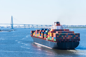 Naklejka premium View on the container ship sailing through the river on her departure from port of Charleston, SC.