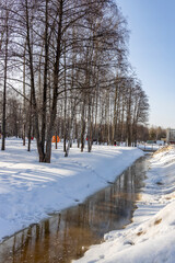 Thaw in the city park, snow melting, accumulated water in the ditch. spring flood, sunny day in the...