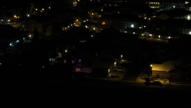 A night aerial view of a colorful condo unit next to a highway, revealing other buildings in the condominium complex.