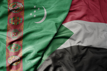 big waving national colorful flag of sudan and national flag of turkmenistan.
