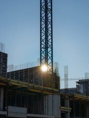 Fototapeta na wymiar Construction crane and construction building under construction against the blue sky and sun