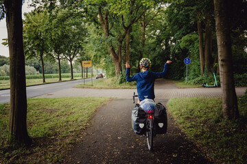 Junge passiert in Siegerpose mit seinem Rad das Ortsschild Münster während einer Radreise durch...