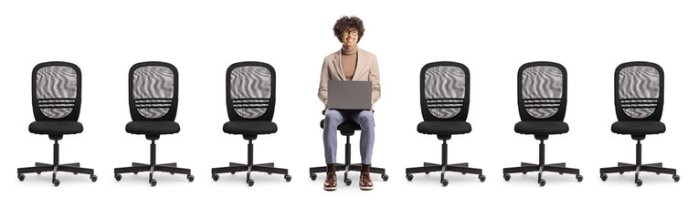 Empty office chairs and a young man sitting and using a laptop computer