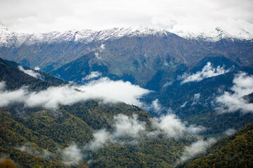 a view of a mountain range with clouds coming out of the valley
