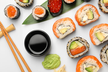 Set of delicious sushi rolls on white background, flat lay