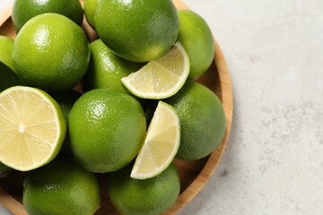 Whole and cut fresh limes on light table, top view. Space for text