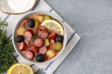 Meat solyanka soup with thin dry smoked sausages served on grey table, flat lay. Space for text