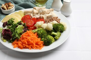 Balanced diet and healthy foods. Plate with different delicious products on white tiled table, closeup
