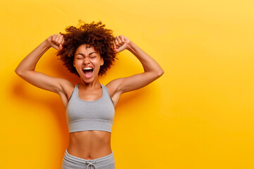An Afro woman with a big smile on her face is doing a fist pump, yellow background