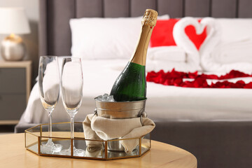 Honeymoon. Sparkling wine and glasses on wooden table in room