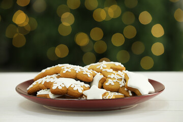 Decorated cookies on white against blurred Christmas lights
