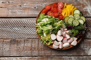 Vegetarian diet. Plate with tasty vegetables on wooden table, top view. Space for text