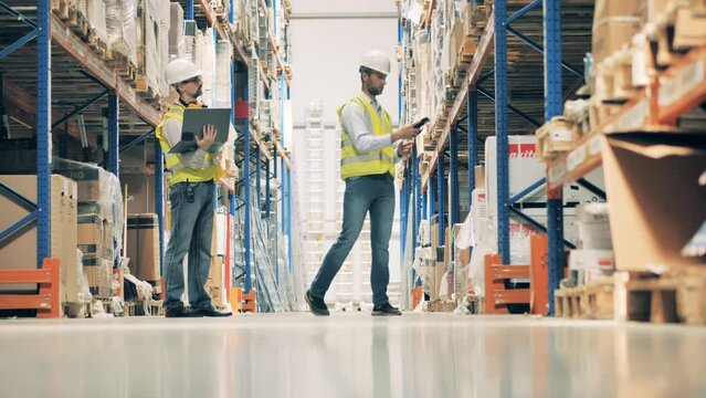 Two warehouse workers discussing goods in stock