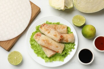 Delicious fried spring rolls served on white marble table, flat lay