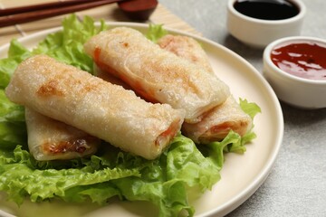 Delicious fried spring rolls served on grey table, closeup
