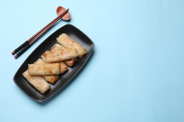 Fried spring rolls served on light blue table, top view. Space for text