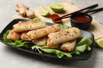 Tasty fried spring rolls served on gray table, closeup