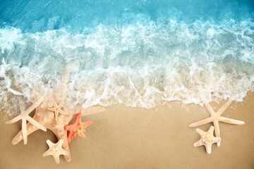 Fototapeta na wymiar Starfishes washed by sea water on sandy beach, flat lay. Space for text