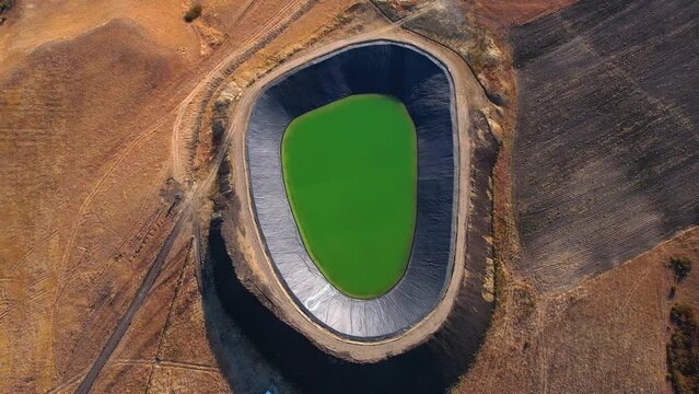 Aerial View of a Water Reservoir in the Desert at Midday.  Aerial shot captures a tranquil water reservoir contrasted by the surrounding arid desert landscape.
