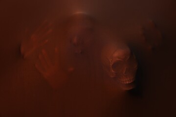 Silhouette of creepy ghost with skulls behind brown cloth