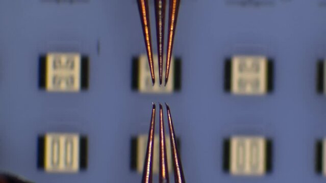 Radio frequency probe touchdown and manipulation on calibration substrate at microchip probing station. Microscope view. 