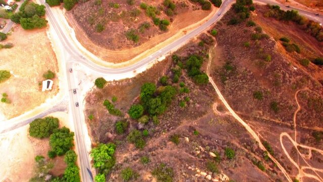 Aerial Tilt Up Shot Of Cars Moving On Road By Houses Over Hill - Simi Valley, California