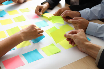 Group of business people working with sticky notes at table in office, closeup